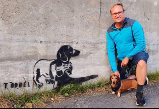 Paul Ove Paulsen og hunden Reinert sammen med et gatekunst av Reinert.
 Foto: Privat/Instagram