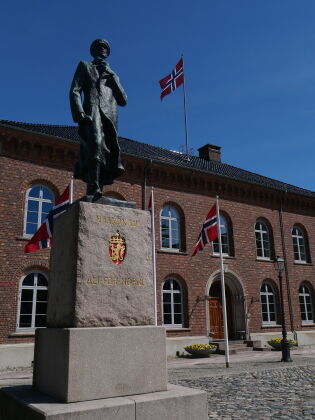 Det norske flagg vinker fra rådhuset i Kristiansand, og statuen av Kong Haakon minner oss på motstanden under okkupasjonstiden.
 Foto: Andreas Collins