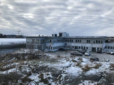 Dette er ett bilde av huset hvor Kristiansand kampsport holder til på Lund. Lokalet ligger rett ovenfor Sør Arena, som er der fotballklubben IK Start trener og spiller hjemmekamper. Sør Arena kan du se i bakgrunnen med snø på toppen. Foto: Emil Madsen Gjørtz.