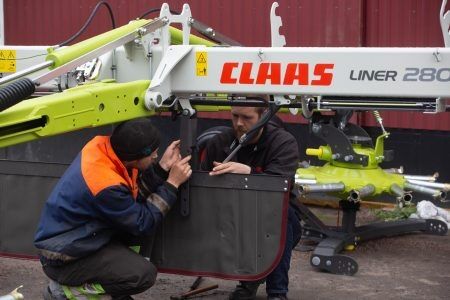 Her er sønnen Lars Osmund og Torkjell i gang med og montere den nye Claas liner 2800 raka. Foto: Sander Netland Bergum
