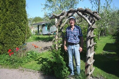 Hans Sørensen viser stolt frem porten inn til den fine hagen sin. FOTO: Maria Køhn