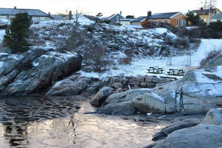 Stranden skal ligge bak de store steinene, men nå er det nesten ikke sand igjen. Foto: Sondre Røhmen