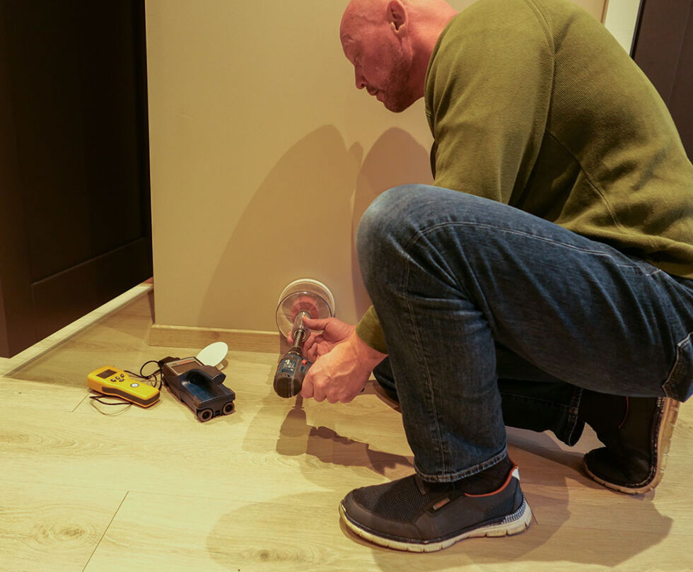 Takstmannen Henrik Løvdal demonstrerer hvordan man måler fuktigheten bak veggen, han må være mer grundig nå, enn før regelendringene. Foto: Vidar Kleiveland