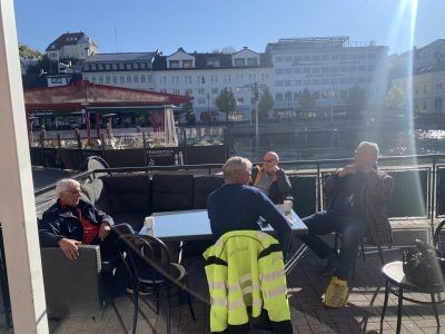 Sola nytes utenfor kafeen. Tore Knutsen (72 år, til venstre) syns det er en trivelig gjeng som samles hver morgen. Foto: Elise-Malen Wårdal.