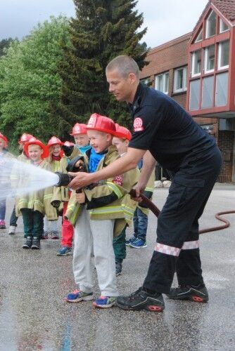 Spyling er gøy: Barna fikk prøve brannslangen en etter en, med god hjelp av brannkonstabel Morten Nygaard. Foto: Julie Sørensen Molvik