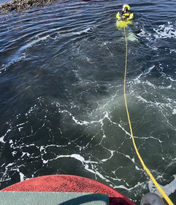 Redningsmann i vannet for å plukke opp 2 personer.
 Foto: Redningsselskapet