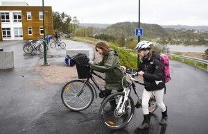 Katrine Sinnes (13) (t.v.)  har lang vei til skolen og sykler over fire mil i uka. Opp siste bakken til skolen triller hun sammen med Eira Tellefsen (13). (Foto: Cecilia Breivold)
